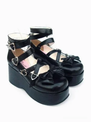 Black lolita platform shoes pair shown in side three-quarter perspective highlighting the heart buckle straps, prominent platform heel, and decorative bow accent