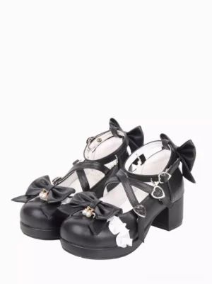 Black Lolita chunky heel pumps with heart-shaped buckle cross straps, bow and ruffle front embellishments, paired shoes front three-quarter view
