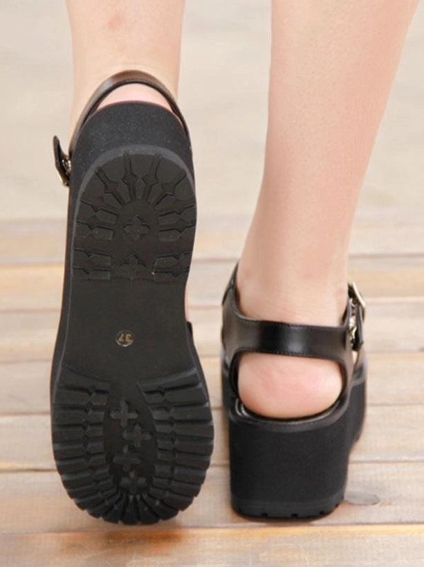 Black gothic lolita platform sandals bottom sole and rear heel view on wooden floor showing non-slip rugged traction pattern and thick block heel construction