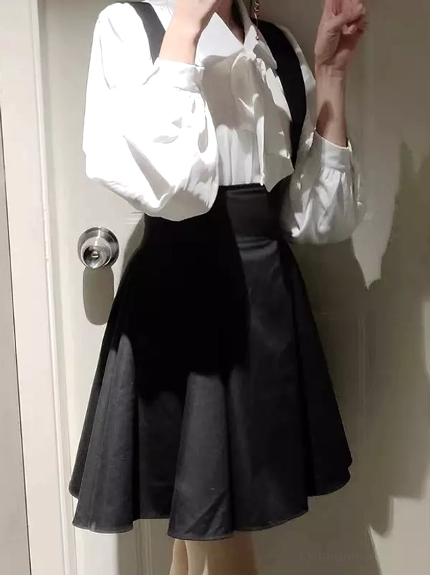 Black lolita suspender skirt front partial view with ruffled neck tie blouse and door background detail