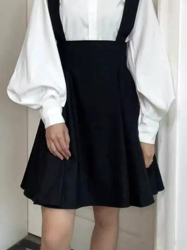 Black lolita suspender skirt front straight view on female model wearing plain collared shirt and indoor background