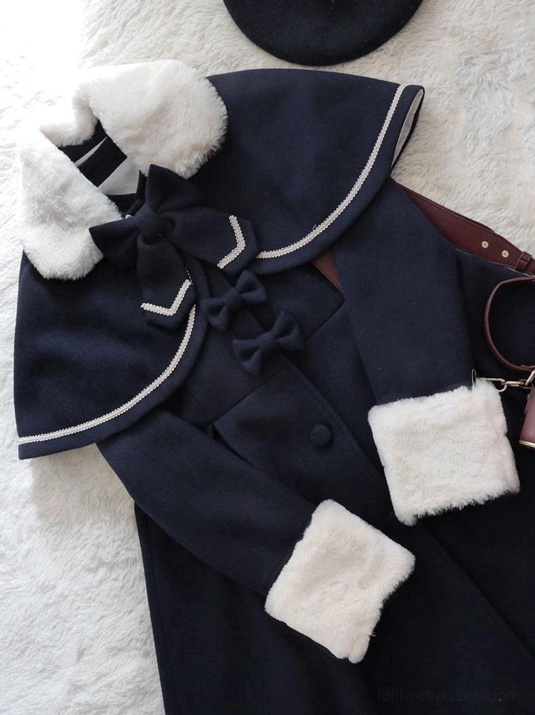 black lolita winter coat close-up flat lay white fur trim bow decorations white piping cape edge faux fur cuffs detail