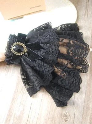 Gothic lolita wrist cuffs with scalloped lace edge sheer mesh underlace and dangling charm accessory arranged on wooden surface with packaging