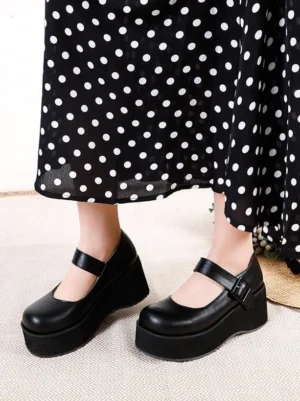 Black Mary Jane platform pumps paired with black polka-dot long skirt, front-facing view of both feet displaying smooth PU material, adjustable ankle buckle, and round toe design
