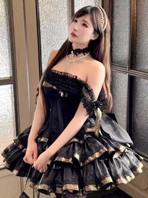 Black off-shoulder sweet lolita JSK dress with tiered ruffle skirt and gold-trimmed layers worn by model near window - front view of authentic lolita fashion piece