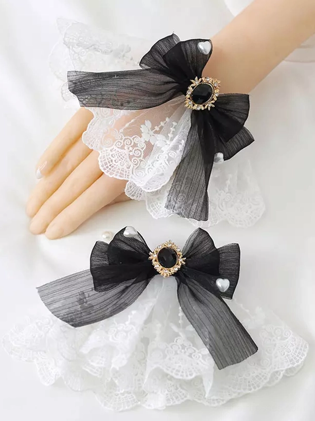 Black organza wrist bow lolita accessory with black gemstone framed in gold and ruffled pearl-embellished lace foundation