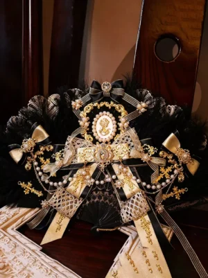 Black ostrich feather folding fan featuring black and gold luxury decorations with pearl accents and refined lace bow, luxury Lolita fashion accessory photographed on elegant wooden table surface