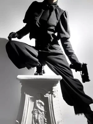 Black Ouji Lolita overcoat with exaggerated bow collar and lace-trimmed puff sleeves, frontal view on model with stone pedestal, all-black Gothic ensemble