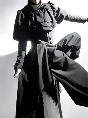 Close-up detail of black Ouji Lolita coat featuring large bow collar, layered waist sash, and intricate lace trim embellishments