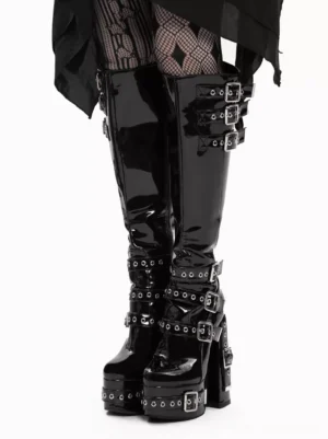 Black patent leather Gothic Lolita platform knee-high boots front three-quarter view with silver buckle straps and chunky block heel, styled with diamond-pattern fishnet tights