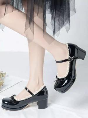 Black patent leather Mary Jane Lolita shoes with front bow and chunky block heel, side view on model feet with black lace tulle skirt and white background
