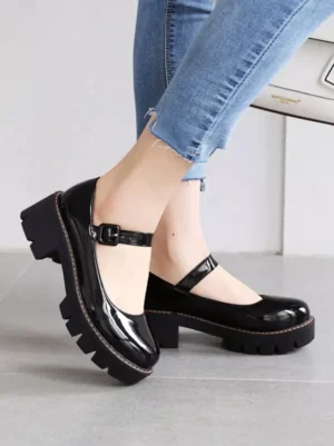 Black glossy patent leather Mary Jane platform pumps with ankle buckle strap and chunky lug sole, worn on-foot from rear side angle showing Lolita shoe details
