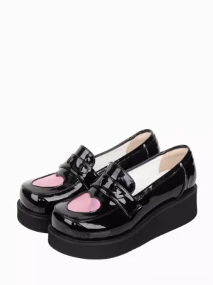 Black patent leather Sweet Lolita platform pumps with holographic pink heart buckle, double shoe oblique front view showing wedge sole and glossy finish