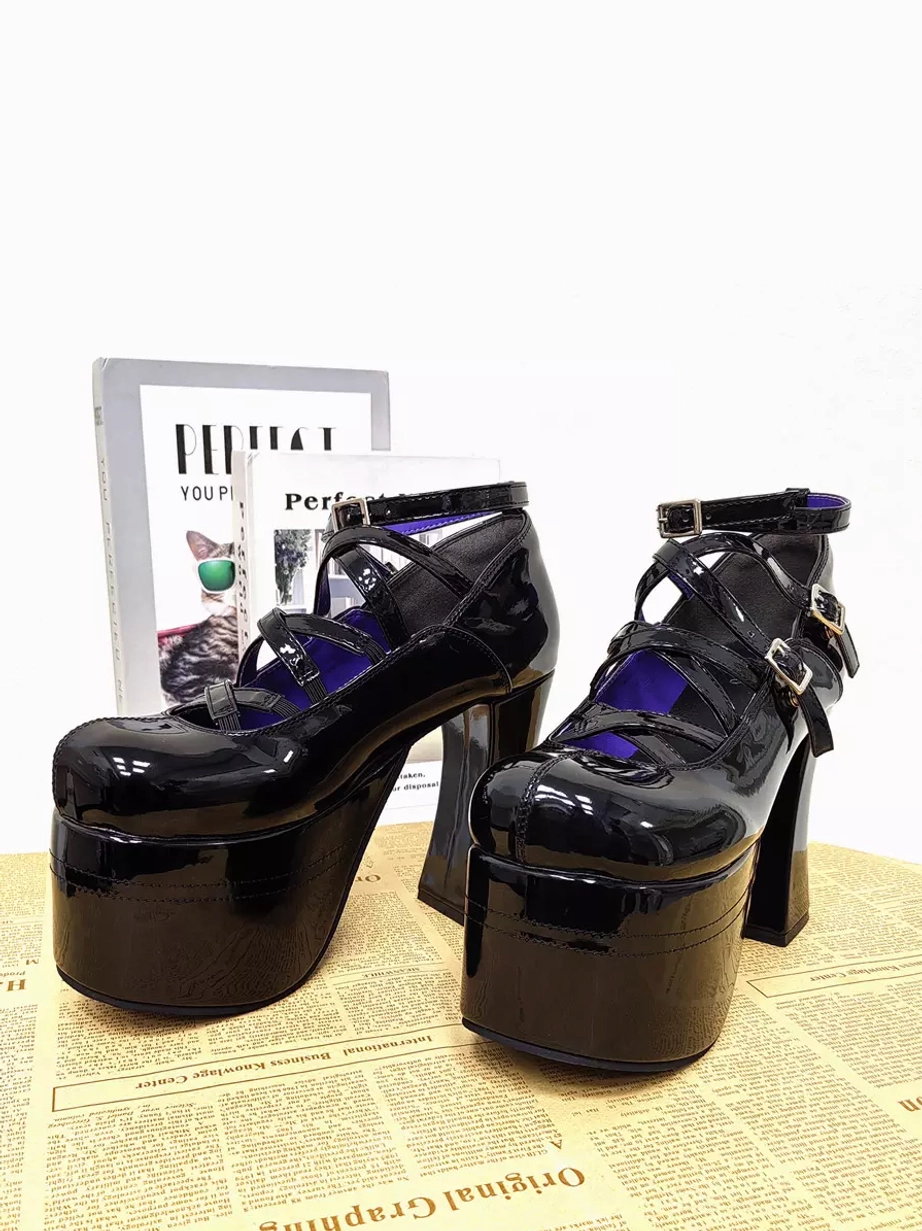 Black patent leather Lolita platform pumps front three-quarter view with decorative props thick platform sole glossy PU surface