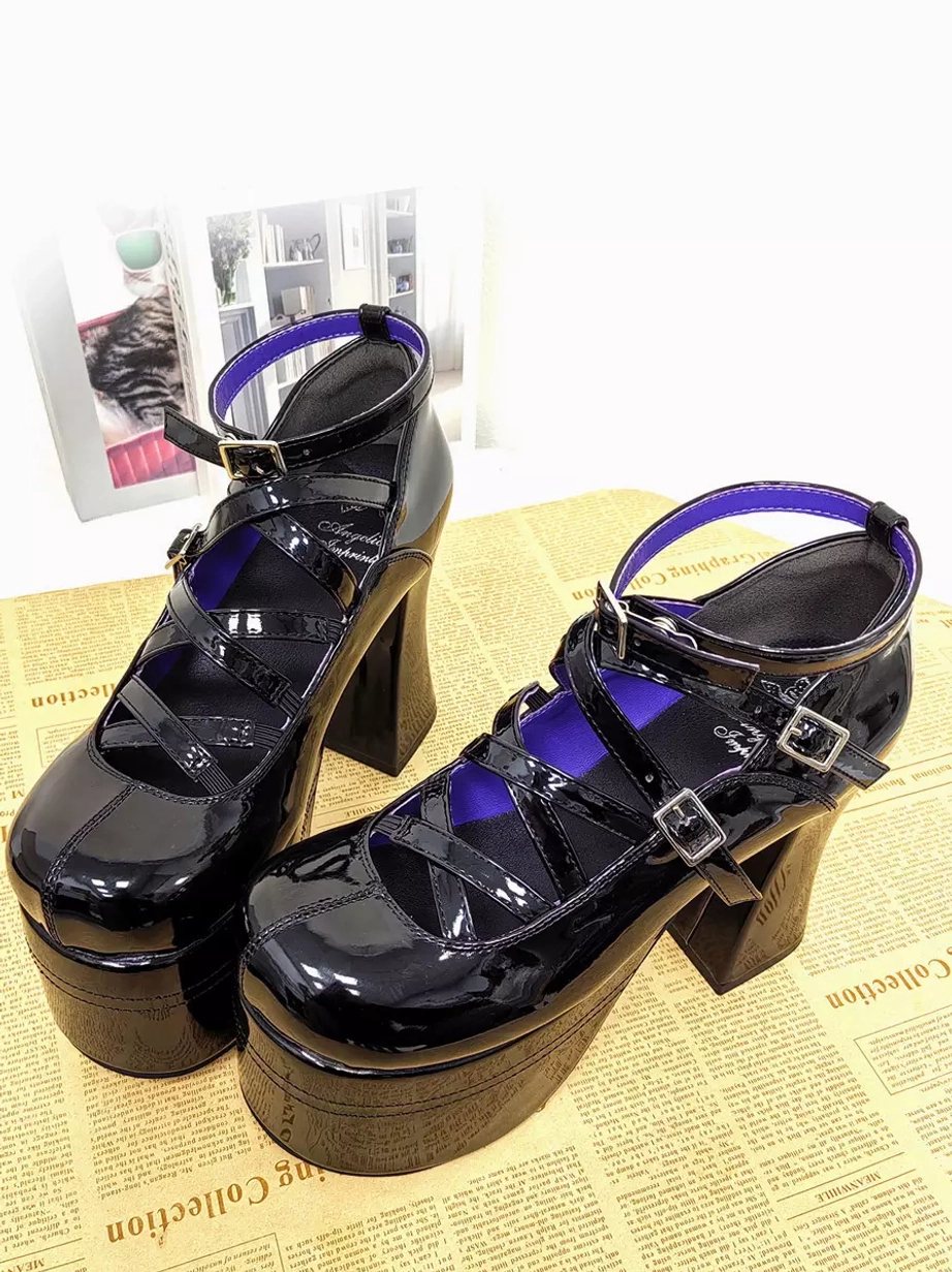 Black patent leather Lolita platform pumps front view on newspaper background showing cross front straps purple inner lining detail