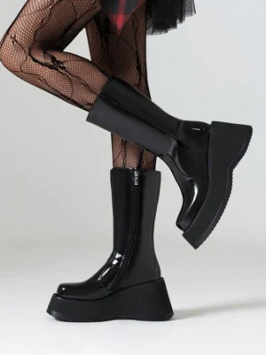 black patent leather platform mid-calf boots side view on model wearing fishnet tights and plaid skirt gothic alternative fashion