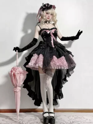 Black and pink fairy lolita dress full-body front view with corset bodice, high-low tulle skirt, pink bow decoration, and rose ruffled hem on blonde model wearing long black gloves and lolita headdress