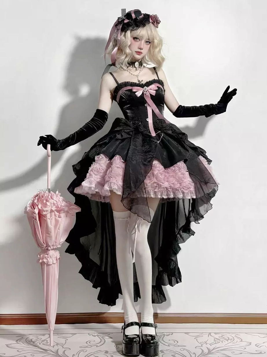 Black and pink fairy lolita dress full-body front view with corset bodice, high-low tulle skirt, pink bow decoration, and rose ruffled hem on blonde model wearing long black gloves and lolita headdress