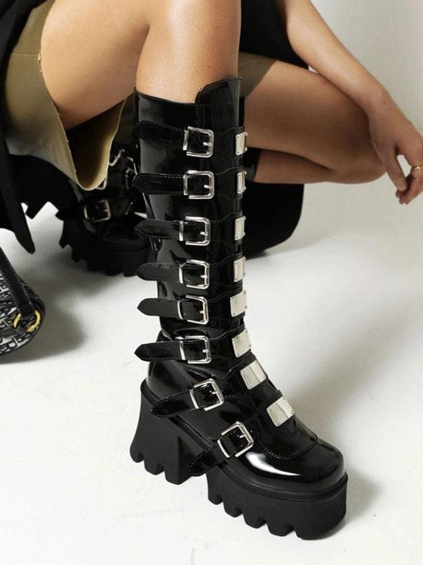 Black glossy platform Lolita boots on model sitting position showcasing lug-patterned sole and patent leather appearance worn styling