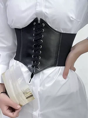 Black PU leather vintage corset waist belt with crisscross lace-up front metal eyelets worn over white blouse close-up front view