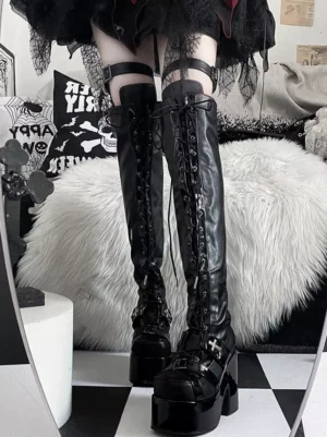 Gothic punk over-the-knee platform boots with lace-up closure, patent leather toe cap, dual thigh straps, and thick platform sole shown in mirror reflection front view in gothic bedroom setting with skull decor and fuzzy rug