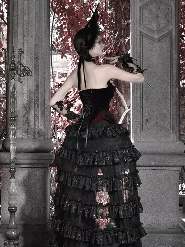 Black and red gothic lolita long skirt with backless corset top and layered ruffled train, full back shooting angle featuring model with low ponytail at stone pillar terrace