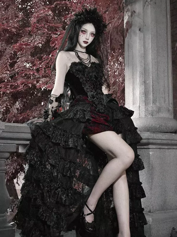 Short black and red gothic lolita skirt with lace ruffled tiered hem and strapless corset top, half side view of model leaning on terrace balustrade with red foliage scenery