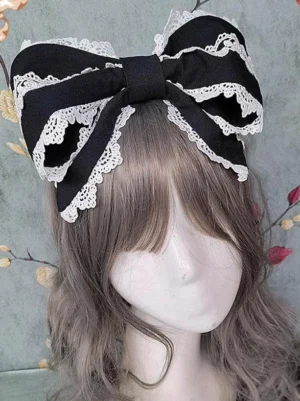 Black Rococo lolita oversized bow headdress with white scalloped lace trim worn on ash brown curly wig close-up front view