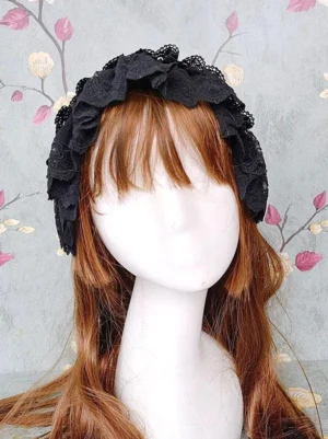 Front facing view of black frilled Lolita headdress with intricate lace trim on mannequin with long brown hair showing solid black lace frilled edges and authentic Rococo aesthetic