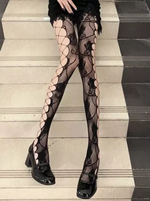 Front leg view of rose patterned black fishnet lolita stockings with lace motifs and skin-toned cutout bases seated on stairs paired with black block heel shoes