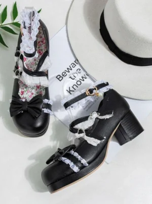 Black ruffled bow Lolita pumps flat lay styled with fedora hat and vintage props showing decorative front bows and chunky heel