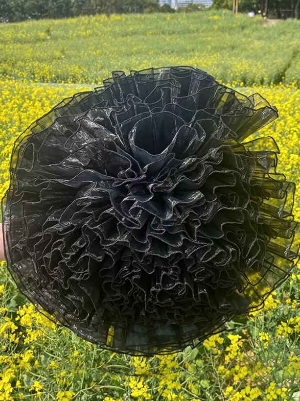 Overhead top-down view of black ruffled organza petticoat showing dense layered ruffles and extremely full fluffy shape for lolita