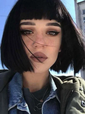 Black short bob lolita wig with blunt bangs worn by model in layered outerwear, classic rococo-inspired sweet lolita hairstyle front view