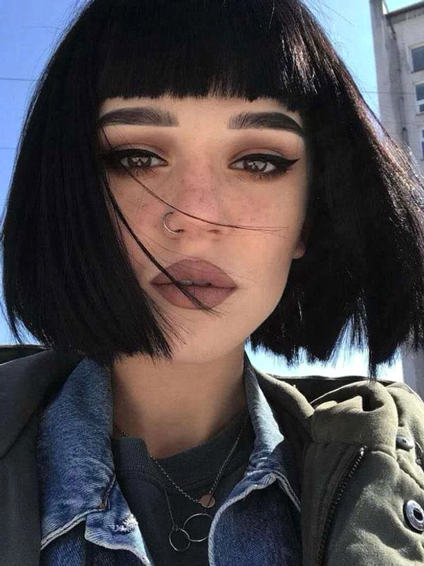 Black short bob lolita wig with blunt bangs worn by model in layered outerwear, classic rococo-inspired sweet lolita hairstyle front view