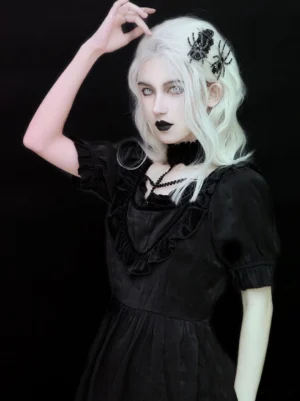 Spider hair pin accessories displayed on model wearing platinum blonde wig and ruffled black gothic lolita dress, front three-quarter view showing two black spider clips on side hair placement