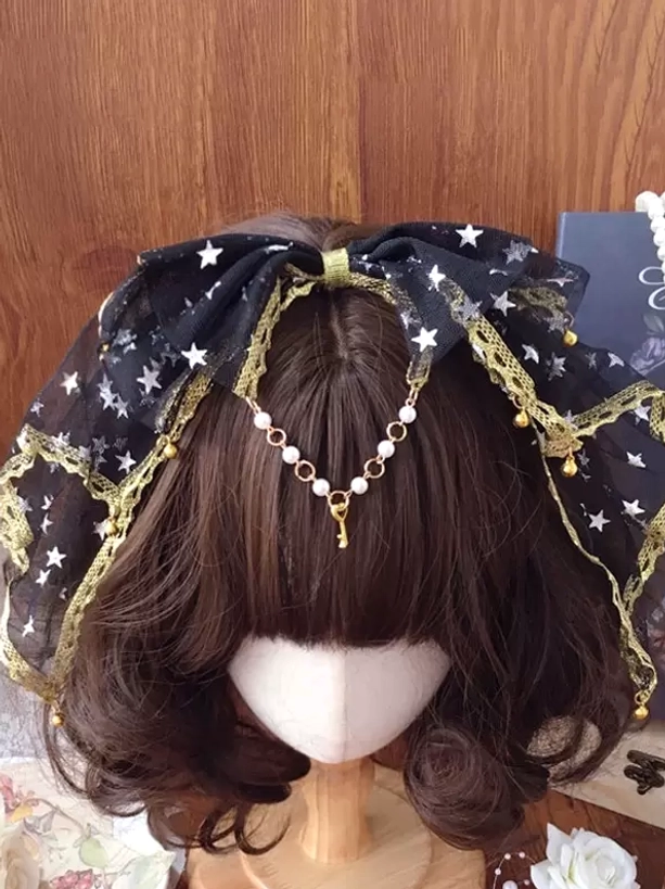 Black star-print tulle lolita bow headband with gold lace trim and pearl forehead chain on wig mannequin with wooden backdrop