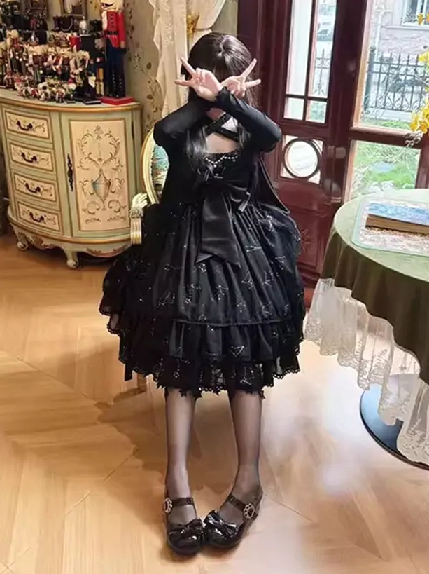 Black star lolita dress back view showing criss-cross halter back design, large back bow, star constellation print skirt, and ruffled lace hem construction