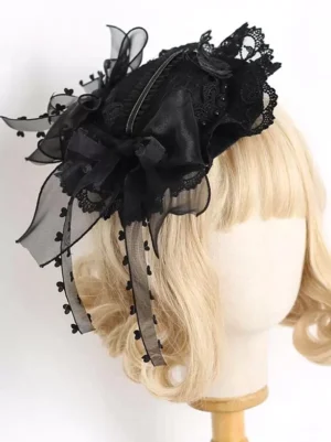 Black steampunk lolita top hat with layered satin bows, heart-dotted organza ribbons, and delicate lace trim, displayed on blonde lolita wig mannequin from right three-quarter angle, showcasing refined Victorian-gothic aesthetic