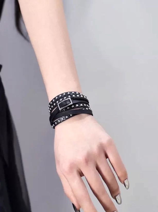 Black studded PU leather multi-layer wrap bracelet worn on female wrist, front view showcasing silver metal rivets and adjustable buckle closure, gothic lolita accessory