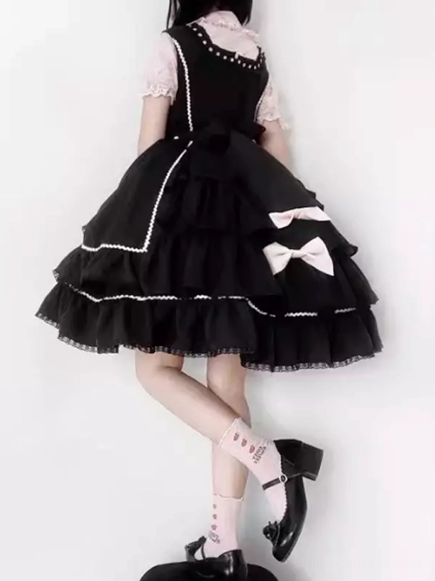 Black Sweet Lolita jumper dress rear view showing large white back bow and layered ruffled hem with lace