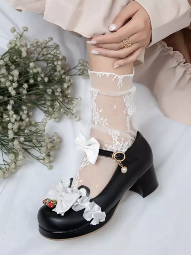 Black Sweet Lolita Mary Jane pumps close-up on-foot shot with hand resting on thigh showing ruffled lace socks, white bows, strawberry charms, and strap charm detail