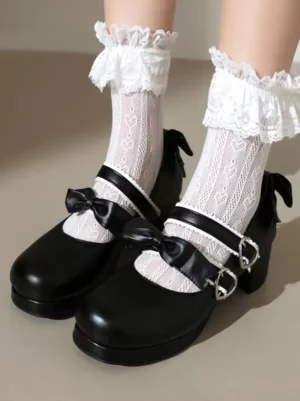 Black Mary Jane sweet lolita pumps with dual heart-shaped buckle straps and bow accents, overhead foot view showcasing round toe design and chunky block heel, worn with ruffled lace ankle socks on neutral indoor surface