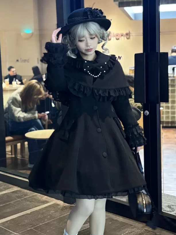 Black sweet lolita overcoat full body side view with ruffled cape collar solid black a-line hem worn by model with grey curly hair and top hat