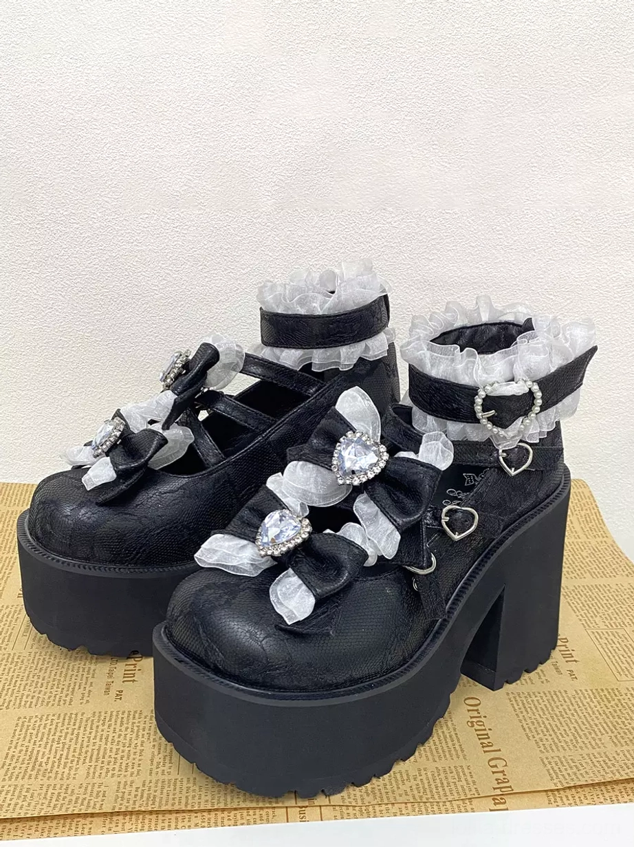 Black sweet lolita platform pumps vintage newspaper background front view with white ruffled straps and heart rhinestone bow decorations