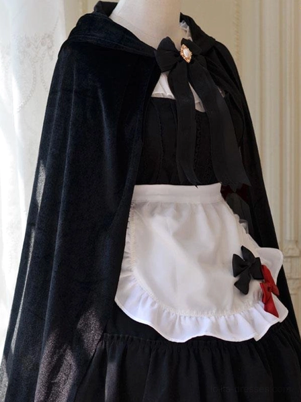 Black velvet gothic lolita poncho cape with gem brooch collar bow and ruffled apron, left front close-up view on display mannequin
