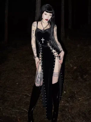 Black velvet gothic lolita slip dress with silver cross accent and lace-up side split worn by tattooed model in outdoor night setting showing full-body view of darkwear aesthetic