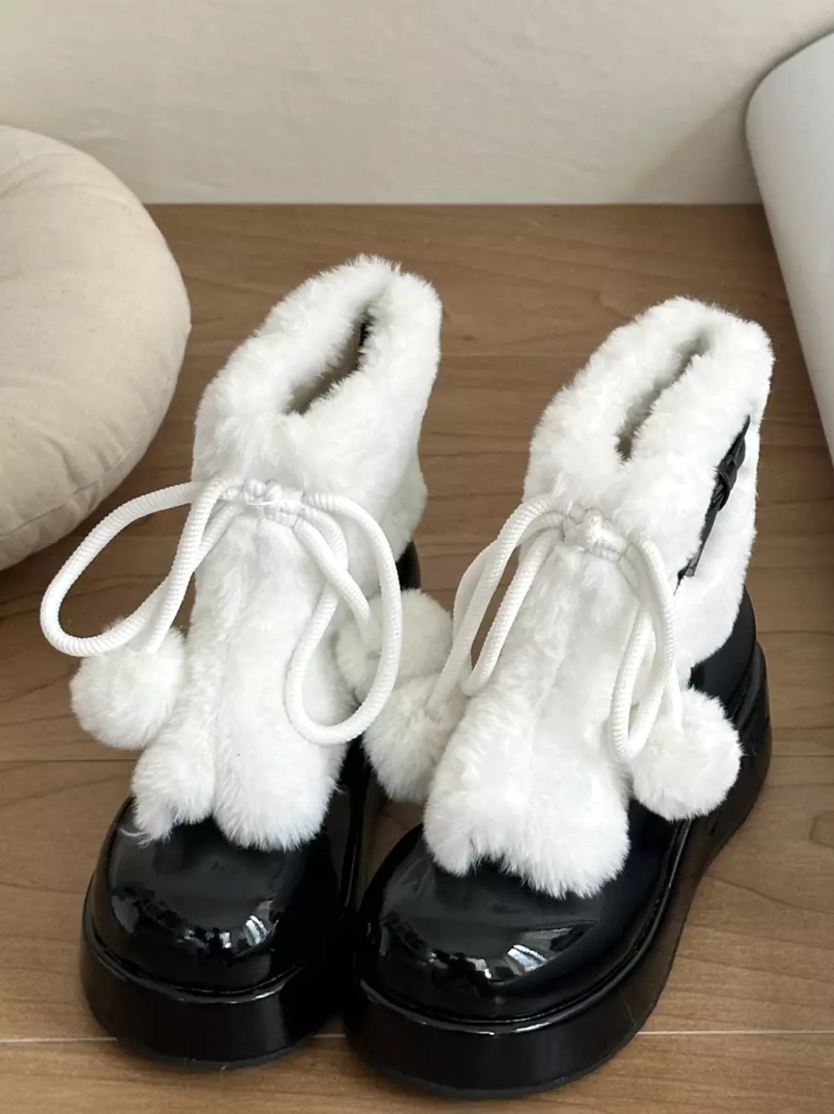 Black and white lolita platform boots front-side angle showing black patent leather sole and pom-pom details