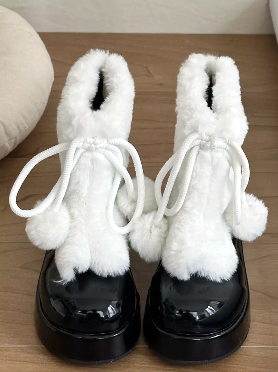 Black and white lolita snow boots front view with pom-pom drawstring and black patent leather round toe