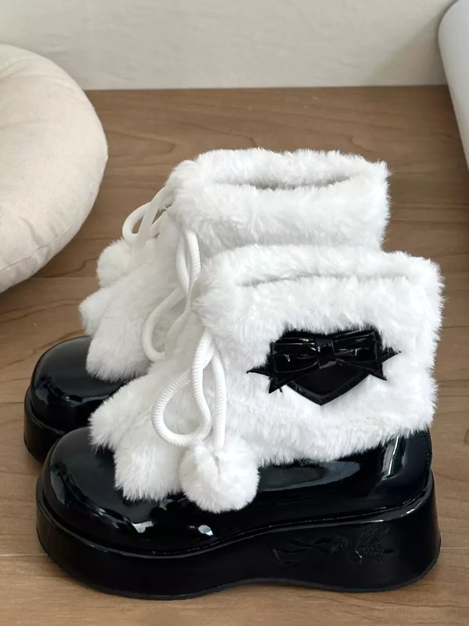 Black and white lolita platform snow boots front view showing fluffy white plush upper and black heart bow embellishment
