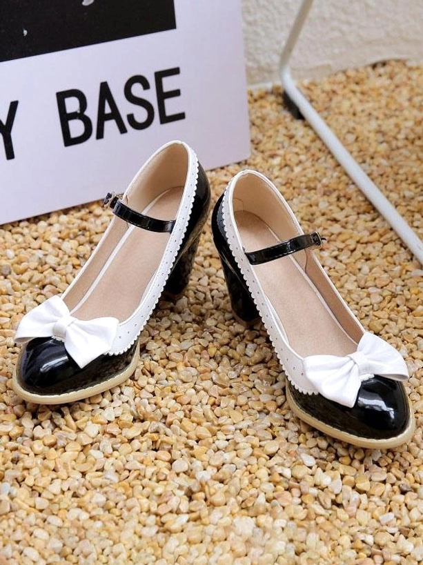 Black and white lolita pumps flat lay top-down view on gravel ground with white bow decoration black ankle strap glossy patent leather